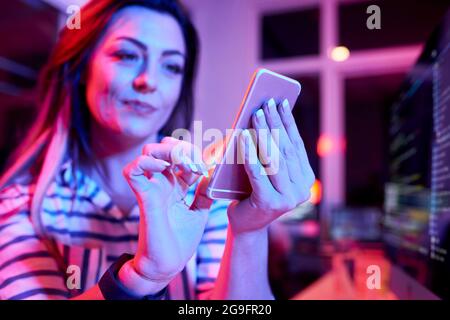 Female coders working in office late at night and testing her new application on smartphone Stock Photo