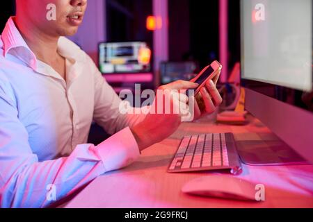 Serious businessman sitting at office table and answering text messages or using mobile application Stock Photo