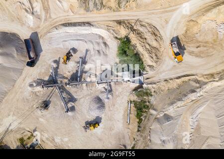 Open pit mining of construction sand stone materials with excavators and dump trucks at conveyor belt. Stock Photo