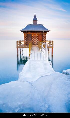 Icy wooden bath house in evening light on Lake Neuchatel in Gorgier, Neuchatel, Switzerland Stock Photo