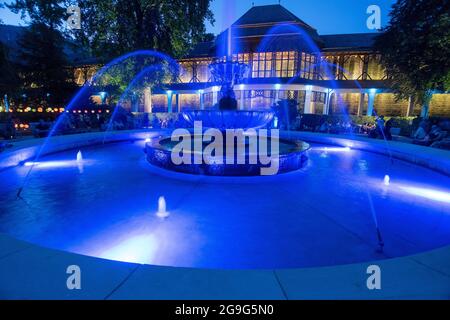 Spa garden lighting in the royal spa garden Bad Reichenhall. The illuminated fountain Solebrunnen in front of the graduation house. Bad Reichenhall, Bavaria, Germany.. Stock Photo