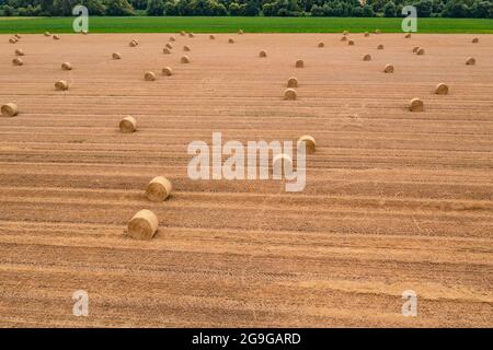 Aerial view of straw bales in a harvested field with a green strip of flowers Stock Photo