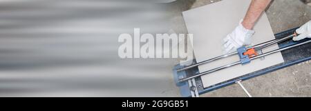 Tiler using a tile cutter on grey background Stock Photo