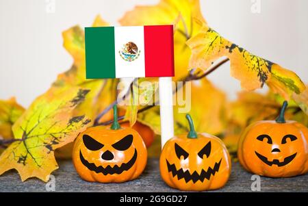 Colorful Halloween background with smiley pumpkins and toy flag of Mexico Stock Photo