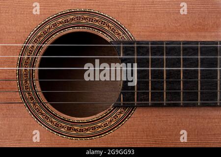 Close-up of old acoustic guitar showing detail of decorative rosette decal around soundhole, strings and part of ebony fretboard. Top down view Stock Photo