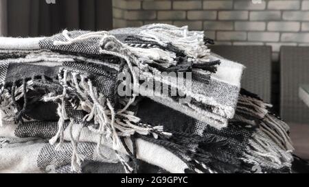 heap of knitted plaids on a gray background. Warm and cozy woolen decor for home and cafe. Gray wall background. Copy space. Gray checkered blanket. W Stock Photo