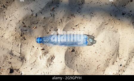 The bottle is plastic. Ecology, plastic pollution. Ocean pollution. Plastic in the sand. Trash on the beach concept. artificial pollution and poster. Stock Photo
