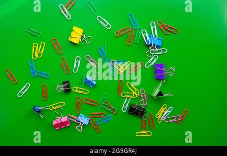 pile of paper clips isolated on green background, documents, office supplies concept, dirty office desk. Empty place for writing and text. Top view, l Stock Photo