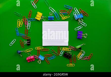 pile of paper clips isolated on green background, documents, office supplies concept, dirty office desk. Empty place for writing and text. Top view, l Stock Photo