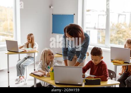 Female teacher explaining the task to schoolchildren Stock Photo