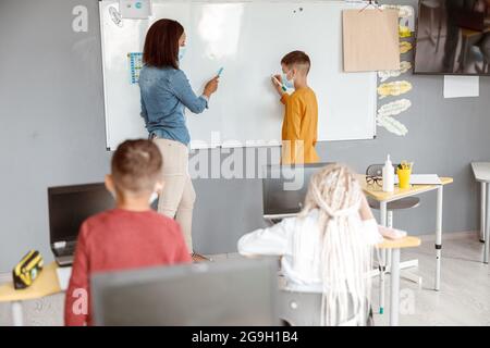 Teacher and schoolboy standing near the blackboard in the classroom Stock Photo