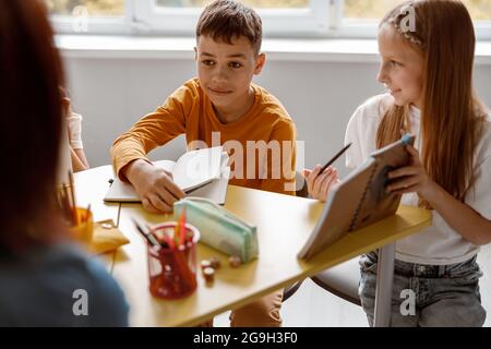 Smiling kids sitting at the table and using notebooks Stock Photo