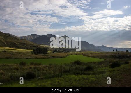 Early morning sunrays, breaking through the clouds, illuminating the Drakensberg Mountains in the Free Sate of South Africa Stock Photo