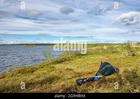 Hiking tent at a lakeshore in the wilderness Stock Photo