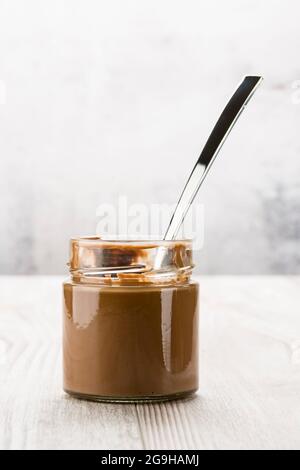 Chocolate cream in glass jar on wooden table Stock Photo