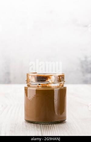 Chocolate cream in glass jar on wooden table Stock Photo