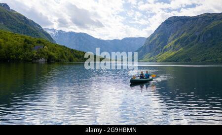Aerial shot of kayakers on the lake, mother and son paddling toward mountains Stock Photo