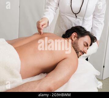 Treatment of back pain and tightness with acupuncture needles for a male patient, Traditional Chinese Medicine. Alternative medicine, reflexology Stock Photo