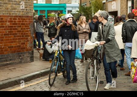 London, UK - November 2019, Mom and daughter in helmets and with bicycles make their way through the crowd Stock Photo