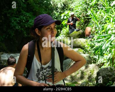 Latin Woman Using a Purple Cap is Sitting and Relaxing in the Middle of Nature Stock Photo