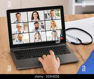Female Doctor At Laptop Video Calling Communicating With Group Of Colleagues Online During Medical Video Conference Sitting Indoor. Collage, Selective Stock Photo