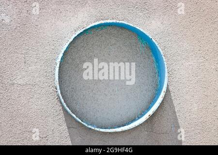 Round structure in a cement wall covered with cracked plaster. Stock Photo