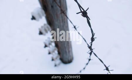 Electric fence with barbed wires in Auschwitz. Nazi Germany's largest concentration and extermination camp. Winter season. Snow-covered landscape. Stock Photo