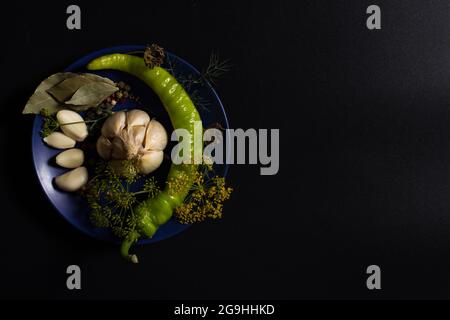 Different fresh herbs and spices on plate on black background with copy space. Stock Photo
