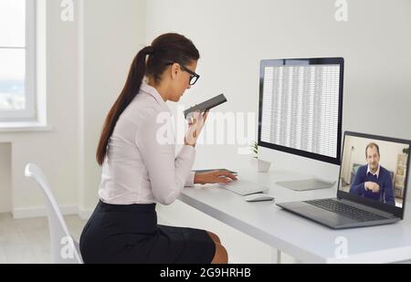 Woman using multiple devices and computers while working at her desk in the office Stock Photo