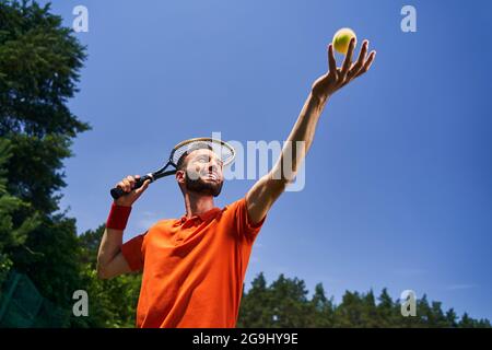 Male tennis player tossing the ball into the air Stock Photo