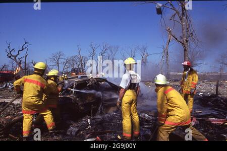 Brenham Texas USA, April 71992:  Firefighters hose down a burned car after a natural gas pipeline explosion leveled a rural area outside of Brenham, killing one person and several cattle, and injuring a score of people. ©Bob Daemmrich Stock Photo