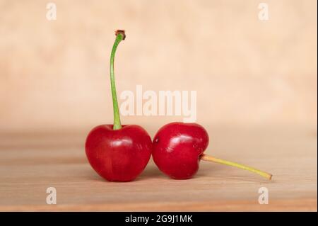 Two Red Cherries with Stems on a Wood Background Stock Photo
