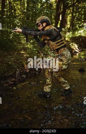 Woman in uniform using dangerous weapon outdoors Stock Photo