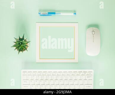 Neat office position, White computer keyboard, Accessories, Creative layout, Bright frame in the center, Place for text, Pistachio color background Stock Photo