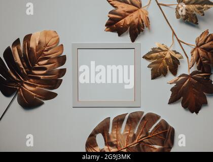 copper golden leaves, in the center of the white frame with a blank space, Creative background Stock Photo