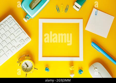 A creative layout of office equipment with a frame in the middle for a note, Yellow, white and blue colors Stock Photo