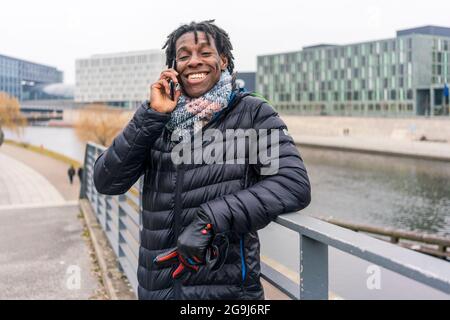 Germany, Berlin, Smiling man using smart phone in city Stock Photo