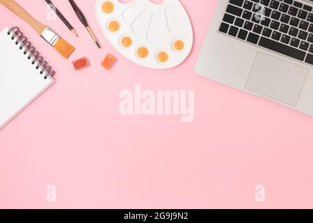 Tools for painting on a pink pastel background. Laptop, watercolor and stationery. Workspace for online study with copyspace. Stock Photo