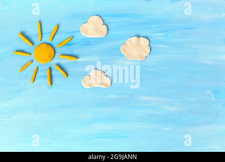 Sun, clouds on blue sky. Made from plasticine Stock Photo