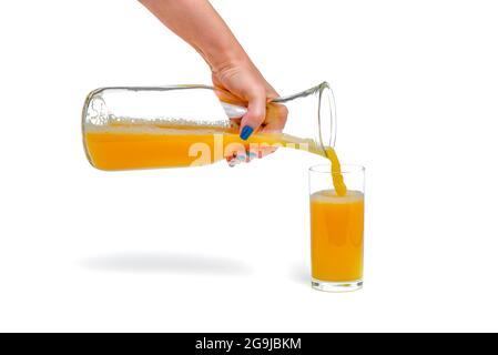 Orange juice isolate. A woman pours orange juice into a glass. Juice filling process on white background, isolated space for design or text insertion Stock Photo