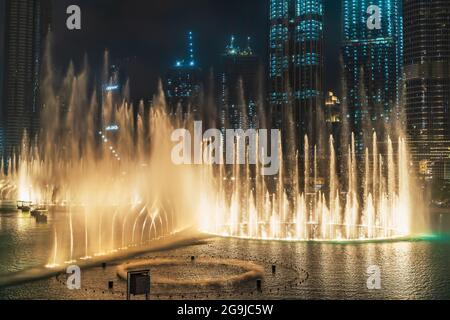 Dubai, UAE - February 2020 : Musical and dancing fountain with lighting in Dubai city at night, UAE. View from balcony at show, skyscrapers and many tourists. Stock Photo