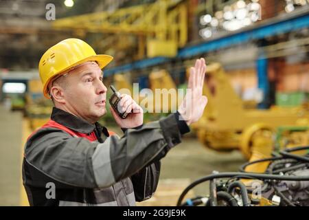Worker in helmet using tablet pc and examining machine equipment in the plant Stock Photo