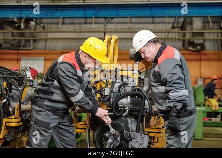 Manual worker in helmet examining the metal equipment in the machinery factory Stock Photo