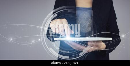 Biometrics identification. White tablet in businesswoman hand with digital hologram Fingerprint scan sign on grey background. Immersive technology fut Stock Photo
