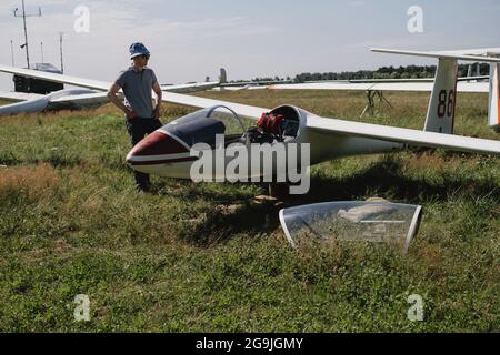 Mature glider pilot in the airplane before flight. Looking at control panel or aircraft on the land. fixed-wing plane without motor. Soaring sport Stock Photo