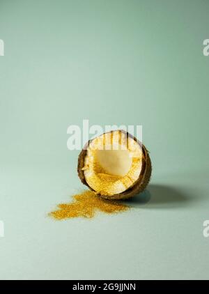 Golden tinsel spilling from cracked half coconut on trendy pastel aquamarine background. Party idea. Minimal summer fun concept. Stock Photo
