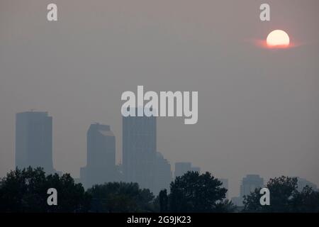 Sun setting through haze over Calgary caused by wildfire smoke from BC during the heatwave. A warning with Air Quality Health Index of 6.6 was issued. Stock Photo