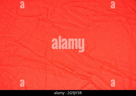 Fragment of genuine leather with wrinkles, artificially dyed light red. Background pattern texture. Stock Photo