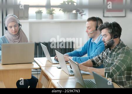 Group of young operators consulting clients online while working in office Stock Photo