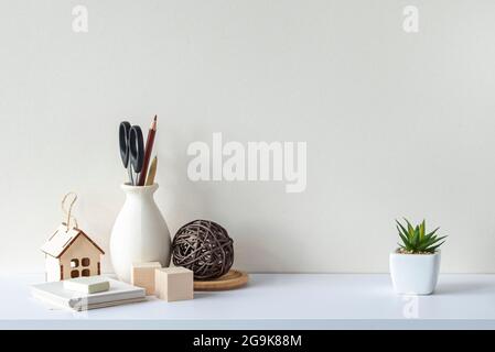 Interior with white desk or shelf, blank wall, stationery, decorative plant. Scandinavian style. Stock Photo